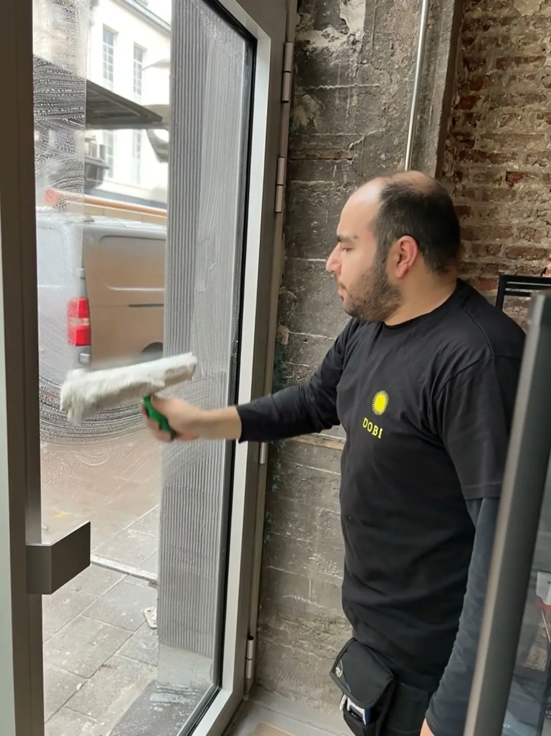 Medewerker wast een grote glaspartij met wisser en verlengsteel