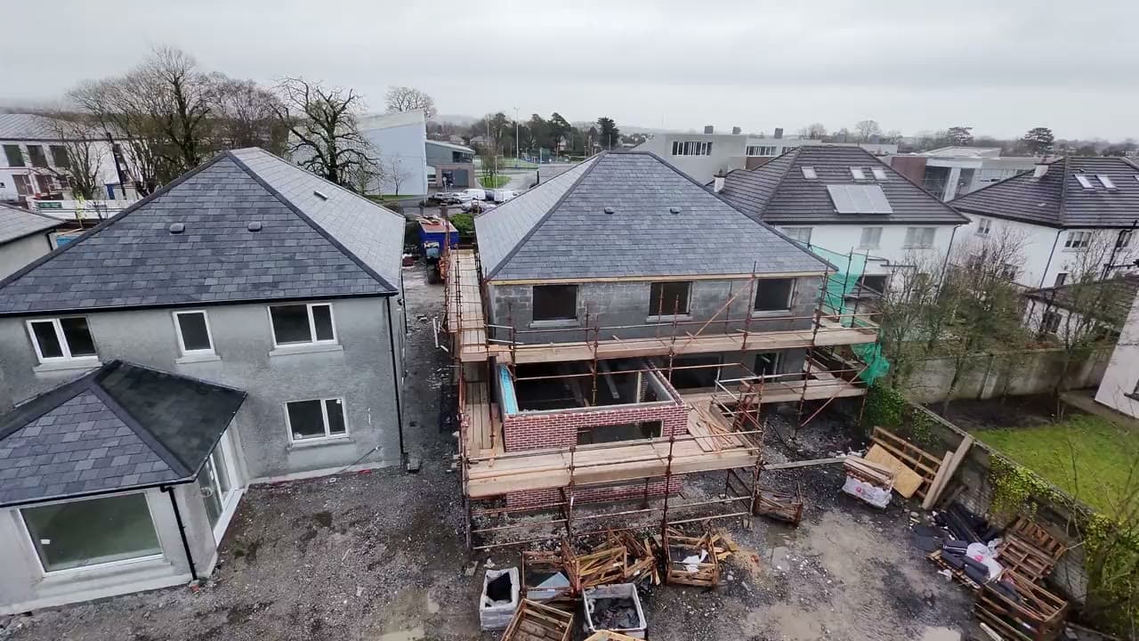 Luchtbeeld van woningen in renovatie met nieuwe leien daken en stelling langs de gevel