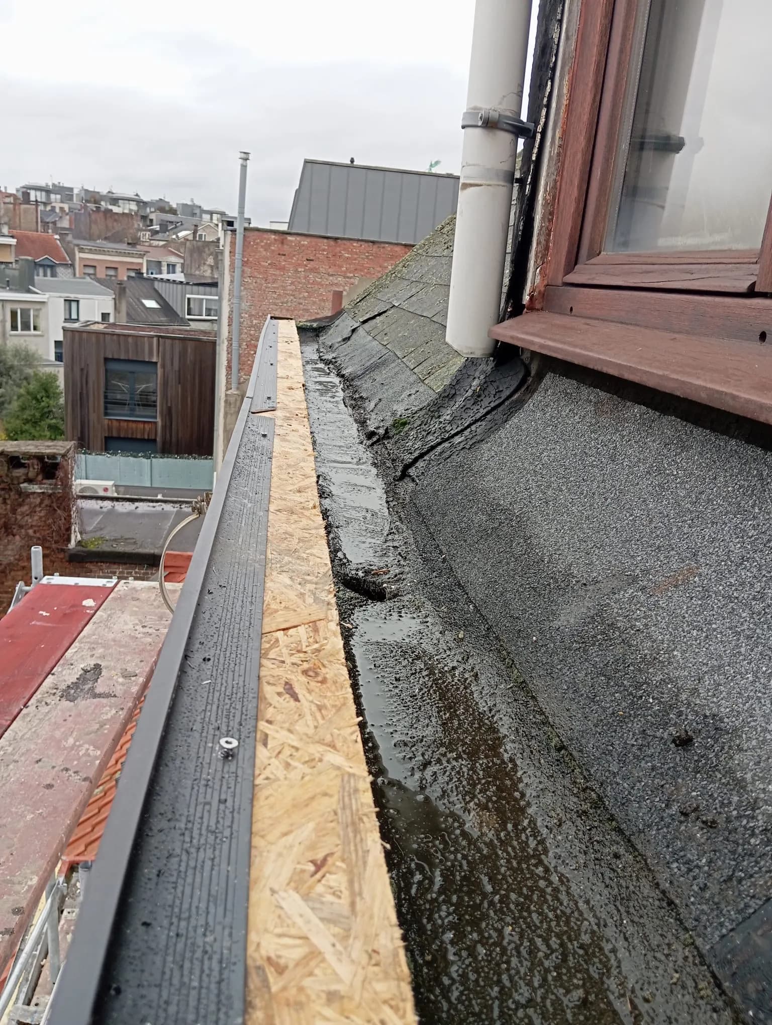 Vernieuwde dakrand met nieuwe OSB-plaat en metalen daktrimprofiel naast de bestaande roofing